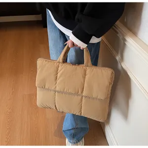 Quilted tote bag detail showing puffy square texture and zipper closure for laptops