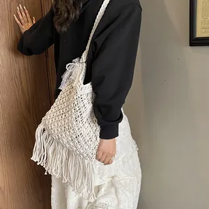 Weiße Boho Häkeltasche mit Fransen und Perlenspitze am Modell für Damen präsentiert