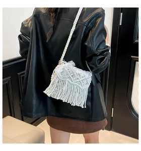 Detail of white handmade woven crossbody bag with tassels and pearls on a model