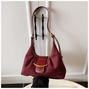 Détail macro d'un sac en daim bordeaux avec boucle corne dorée et plis latéraux