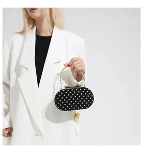 Close-up of black polka dot handbag with golden ring handle and bow clasp detail