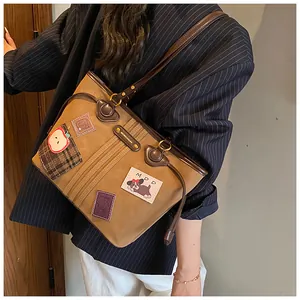 Détail d'un sac cabas marron vintage avec écussons rétro sur matière mate texturée