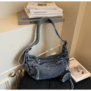 Detail der vintage gewaschenen Denim Hobo-Bag mit kleinem runden Beutel vor Büchern