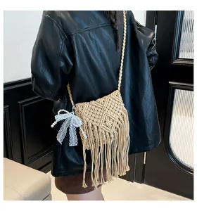 Detail of woven cotton crossbody bag with tassel fringe and lace bow on a model