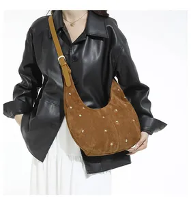 Détail d'un sac hobo en daim marron avec clous dorés et bandoulière réglable sur modèle
