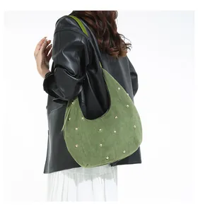 Vue détaillée du sac hobo en daim vert olive avec rivets dorés porté à l'épaule