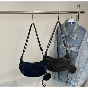 Detail der vintage gewaschenen Denim-Halbmond-Umhängetasche mit Reißverschluss und Fransen