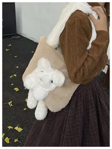 Detail view of khaki plush tote bag with white teddy bear plushie on autumn model