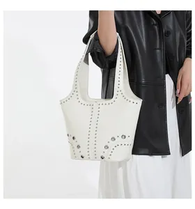 Detail of white tote bag featuring metallic silver studs and grommets on wide shoulder strap