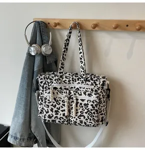 Detail of leopard print tote bag featuring front zipper pockets and adjustable white strap
