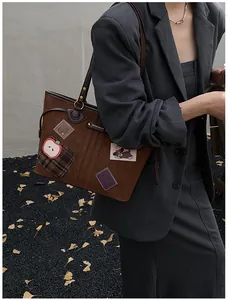 Détail d'un sac cabas marron foncé vintage avec écussons ludiques et anneaux en métal