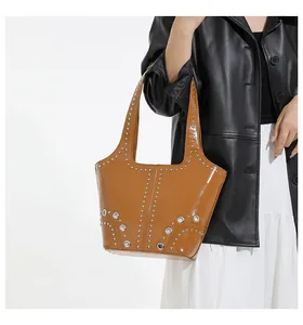 Close-up of caramel tote bag with silver rivets and eyelets on a fashion model