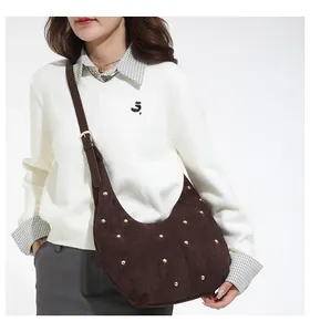 Détail du sac hobo en daim marron foncé avec rivets dorés porté par un mannequin