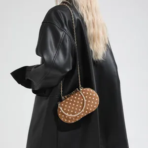 Brown velvet polka dot handbag with gold chain strap for women on a dark jacket