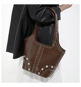 Detail of dark brown leather underarm bag with silver metal rivets and punk style details