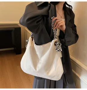 Detail of off-white canvas tote bag featuring black and white striped rope handles