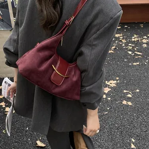 Sac bandoulière chic en daim bordeaux avec boucle en croissant doré sur modèle