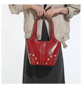 Detailed shot of trendy red studded shoulder bag featuring silver rivets and glossy leather