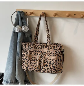Detail of leopard print tote bag featuring three front zipper pockets and woven pullers