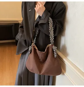 Detail of dark brown faux suede tote with knotted black and white striped woven strap
