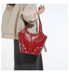 Close-up of glossy red patent leather handbag with silver studs and metal eyelet details