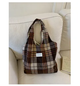 Detail of vintage plaid canvas tote bag with woven label on soft fabric background
