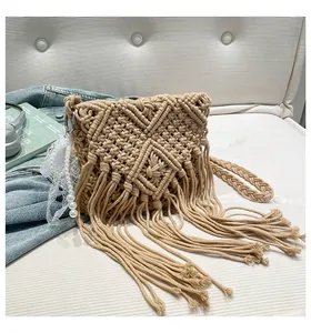 Detailed macro of a beige hand-woven bohemian bag featuring long fringe and pearl charm