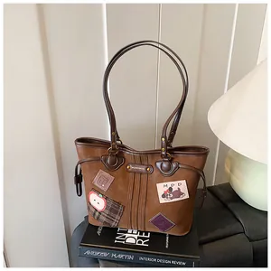 Détail du sac cabas marron vintage en daim avec écussons brodés et doubles poignées