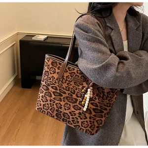 Detailed close-up of leopard print tote bag with leather handles and wooden bead charm