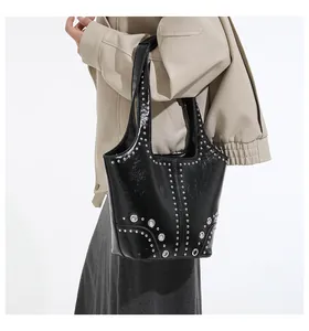 Close-up of black glossy rivet shoulder bag featuring silver metal eyelets and studs