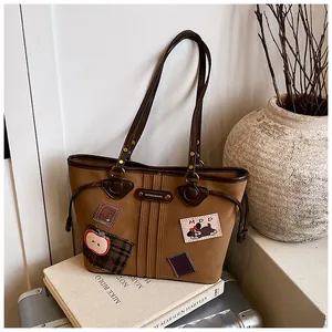 Détail du sac cabas vintage marron avec écussons de dessins animés et boucles en métal
