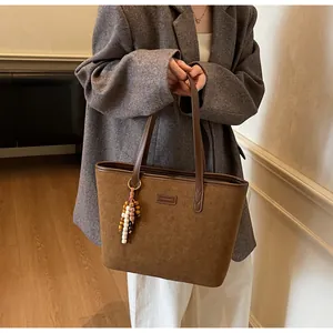 Detail shot of vintage brown matte suede tote bag featuring a colorful beaded tassel charm