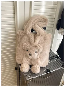 Detail of plush beige tote bag featuring a 3D teddy bear design on a silver suitcase