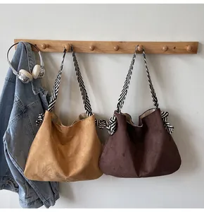 Detail of camel and dark brown suede tote bags with striped woven straps and bow knot accents