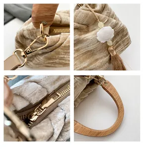 Detail of wooden handle, gold hardware, and lotus tassel on velvet handbag