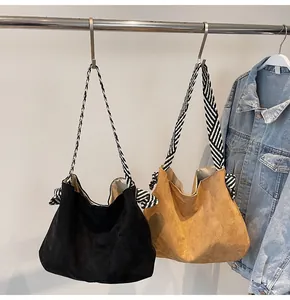 Detail view of suede hobo bags in black and brown with striped woven shoulder straps