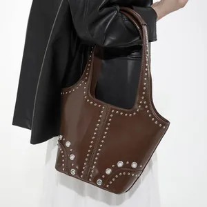 Brown leather punk shoulder bag with silver rivet studs and grommets worn by model