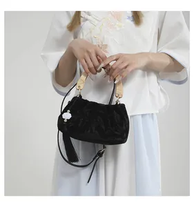 Detail of velvet handbag with floral texture, wooden handle and elegant silk tassel