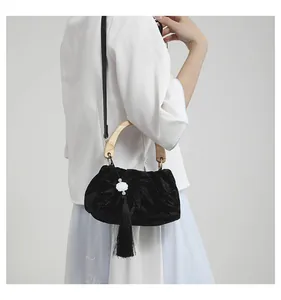 Detail of velvet bag with bamboo pattern, wooden handle and delicate white flower tassel