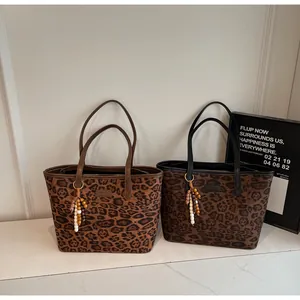 Detail of leopard print tote bags with leather trim and ethnic beaded charms