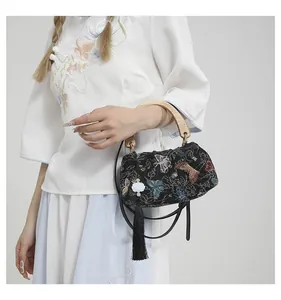 Detailed close-up of embroidered butterflies and elegant wooden handle on black velvet bag