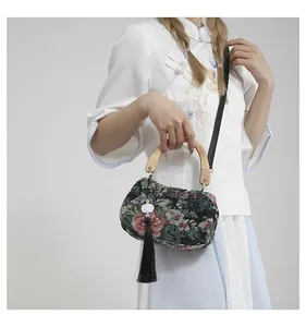 Detail view of ethnic floral jacquard handbag with wooden handle and tassels