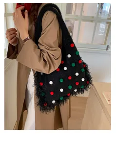 Close-up of black plush tote bag with festive red white and green pom-pom details