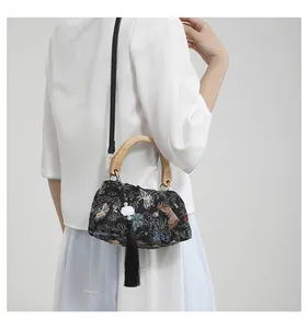 Detail of black embroidered handbag with wooden handle and tassels in Neo-Chinese style