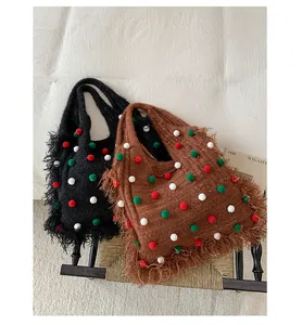 Detail of knit shoulder bags with festive pom-poms and long fringe textures