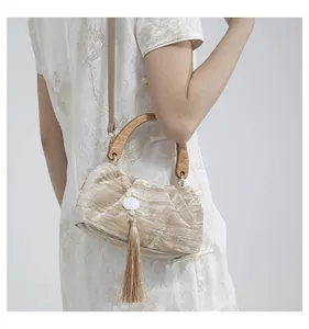 Detail view of champagne velvet cloud bag with wooden handle and elegant tassels