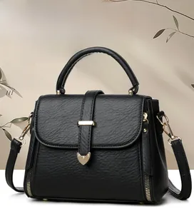 Detail of black pebbled leather handbag featuring gold hardware and a top handle