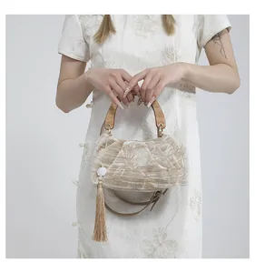 Detail of velvet handbag with wood handle, floral tassel and embroidery on qipao