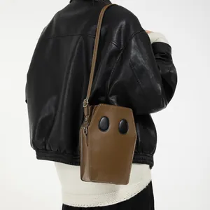 Quirky brown coffin-shaped crossbody bag with adjustable strap and leather texture