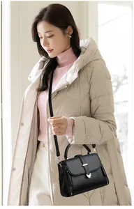 Detailed shot of black litchi pattern leather bag with golden buckle on a model